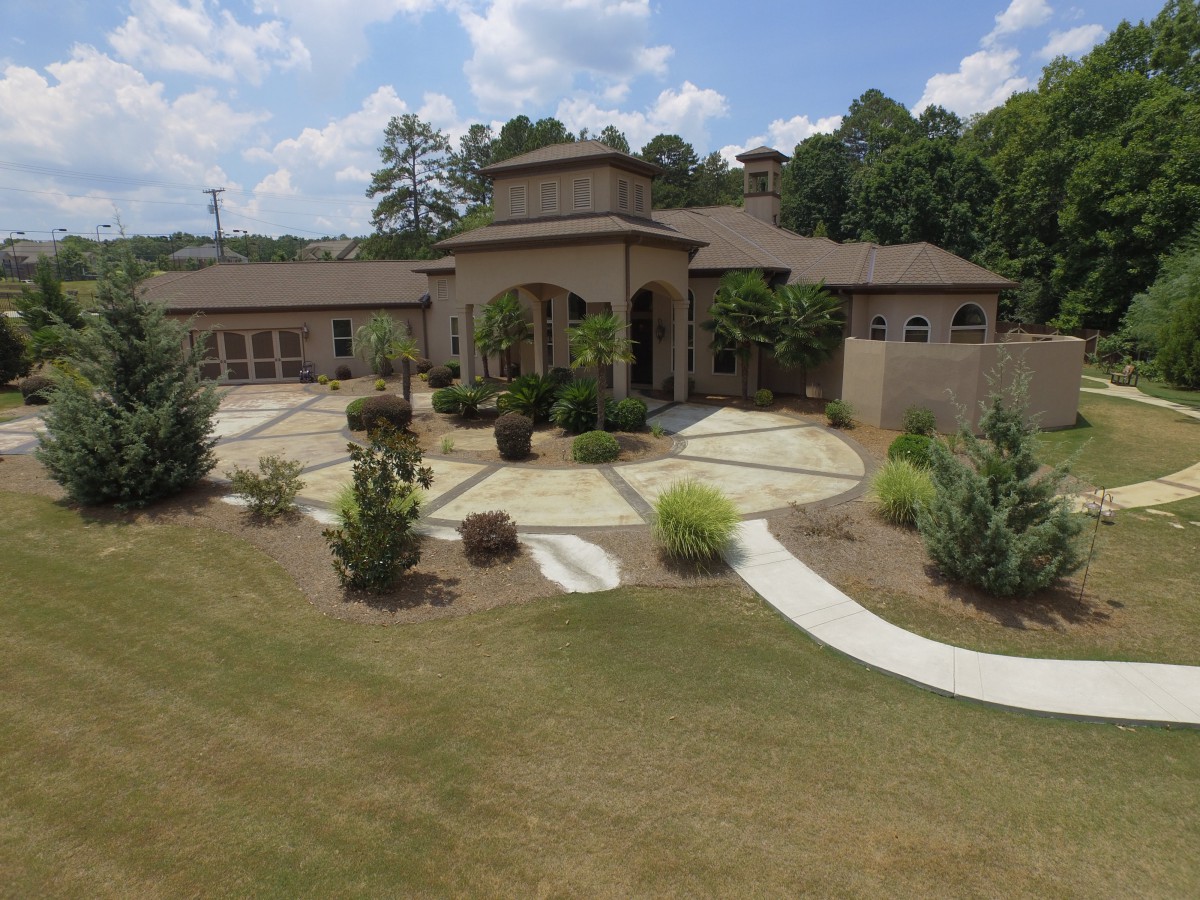 A luxurious house surrounded by a well-maintained garden and trees.