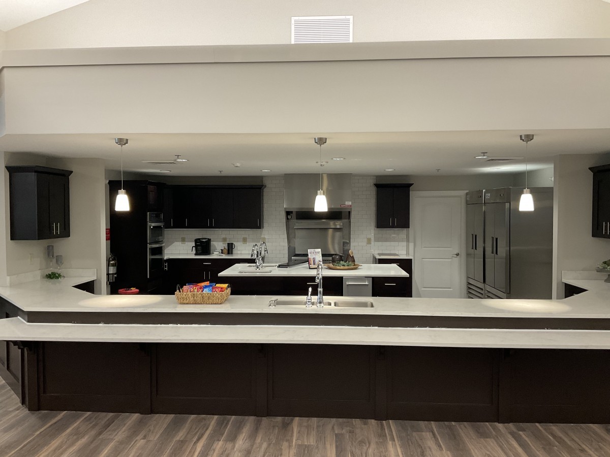 A modern kitchen with a large counter and pendant lighting.
