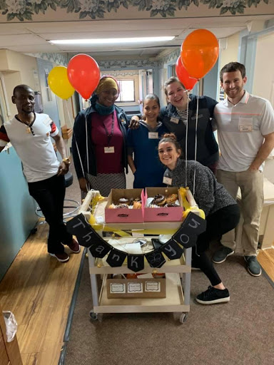 A cheerful team celebrating with balloons and desserts.