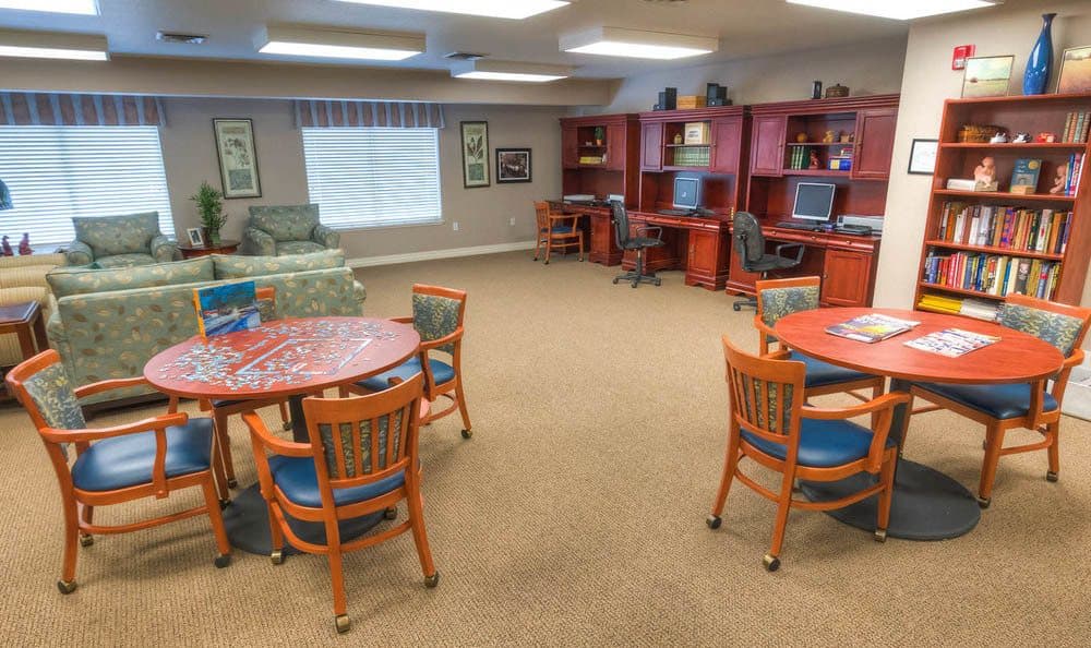 A spacious interior room with tables, chairs, and computer workstations.