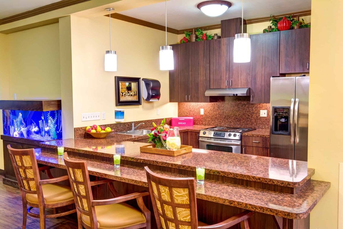 A modern kitchen with a sleek countertop, bar stools, and well-lit pendant lighting.