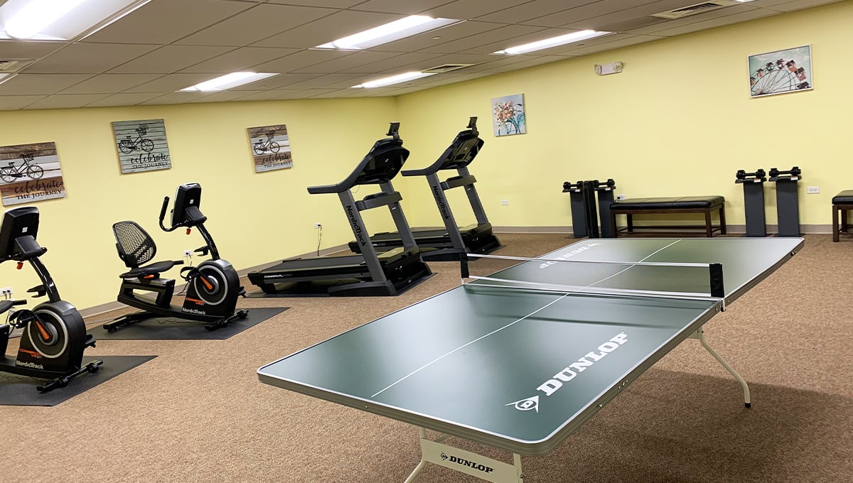 A small gym with treadmills, an exercise bike, and a ping pong table.