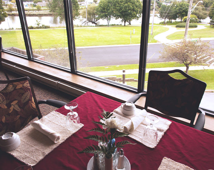 A neatly set dining table by a large window offering a scenic outdoor view.