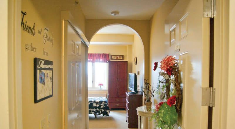 A cozy hallway view leading into a warmly decorated room with an arched doorway and floral arrangements.
