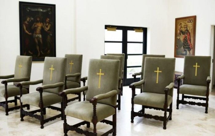 A room with upholstered chairs featuring embroidered crosses, likely a religious or church setting.