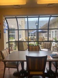 A dining area with a table and chairs, overlooking a patio through large windows.