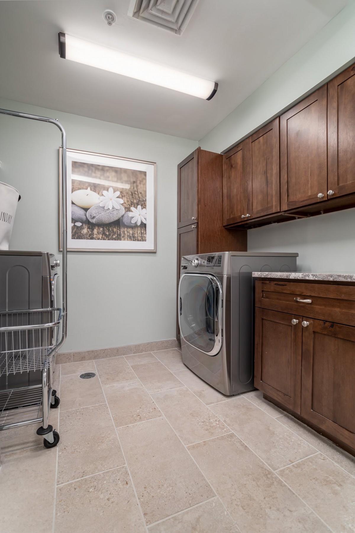 A modern laundry room featuring a washing machine, dryer, and ample cabinet space.