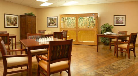 A cozy room with a chess set on the table, surrounded by comfortable seating and artwork on the walls.