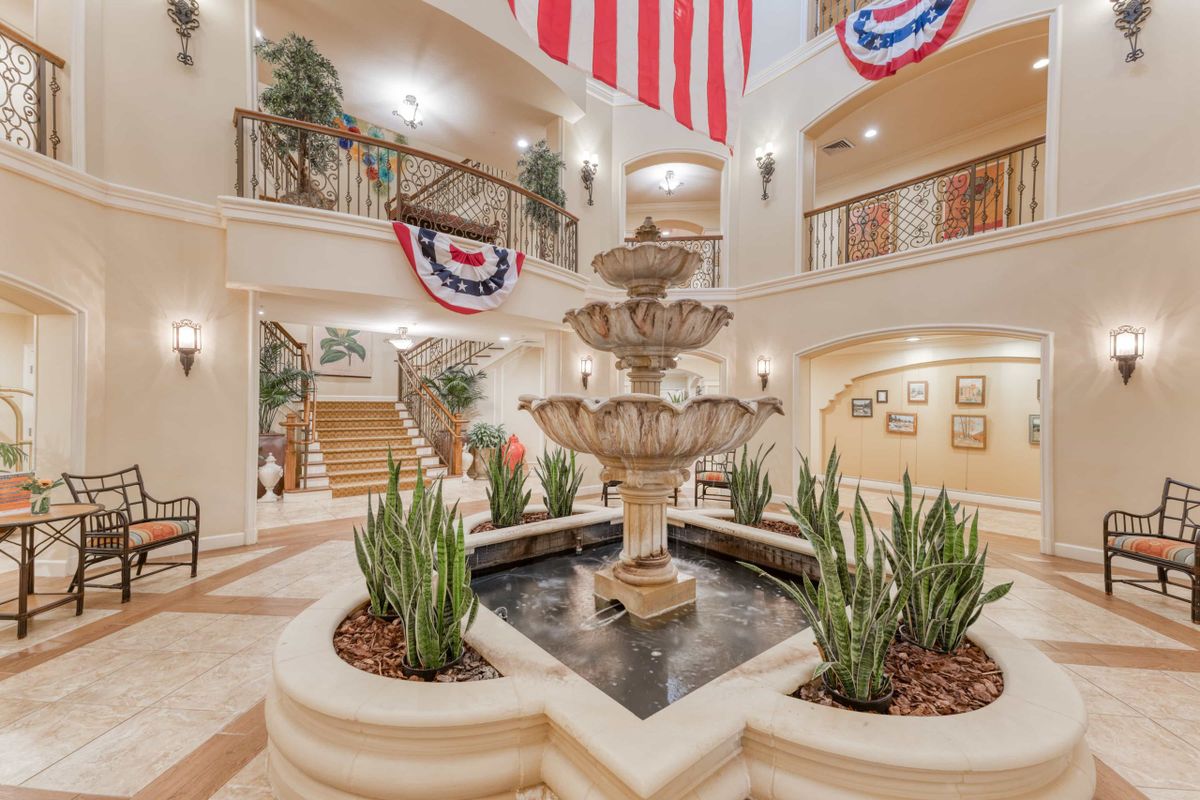 A grand interior atrium featuring a central fountain, surrounded by plants and adorned with patriotic banners.