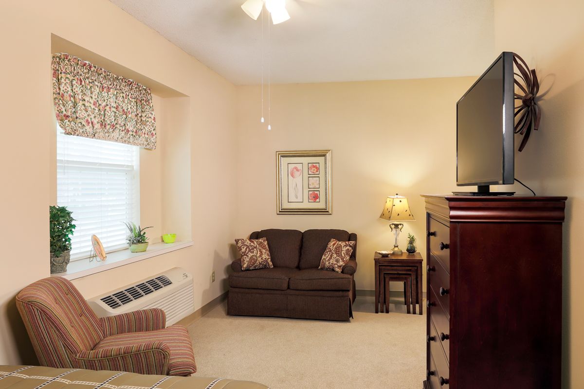 A cozy living room with a sofa, television, and lamp against beige walls.
