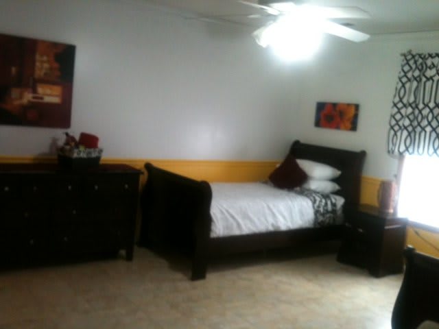 A simple bedroom with a bed and dresser, featuring minimalist decor.