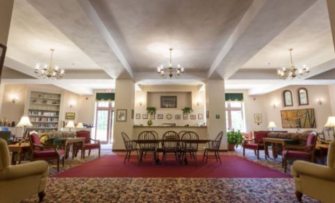 A spacious lobby with elegant furniture and decor, featuring a chandelier and multiple seating areas.