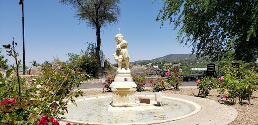 A charming fountain featuring a statue, surrounded by lush greenery and blooming flowers.