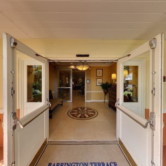 A welcoming entrance with glass double doors leading to a well-lit lobby area.