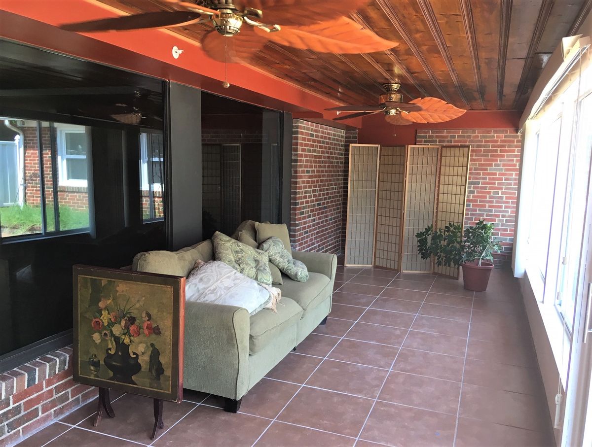 A cozy indoor space with a sofa, brick walls, and wooden ceiling.