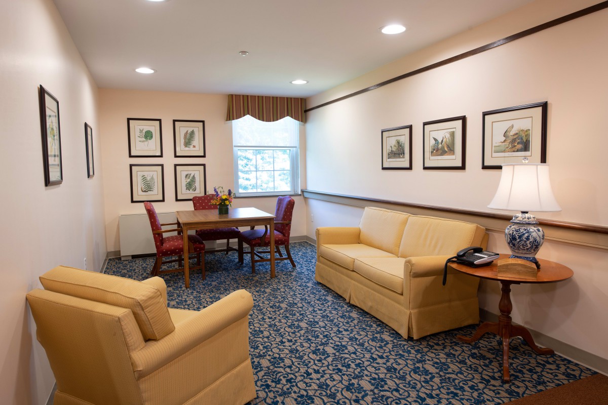 A cozy living room with comfortable seating, a table, and framed artwork on the walls.