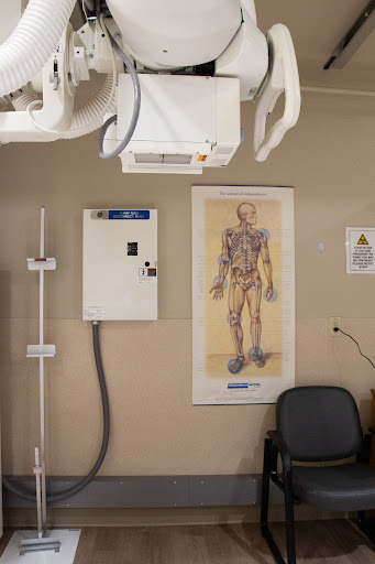 An examination room featuring an anatomy poster and x-ray equipment.