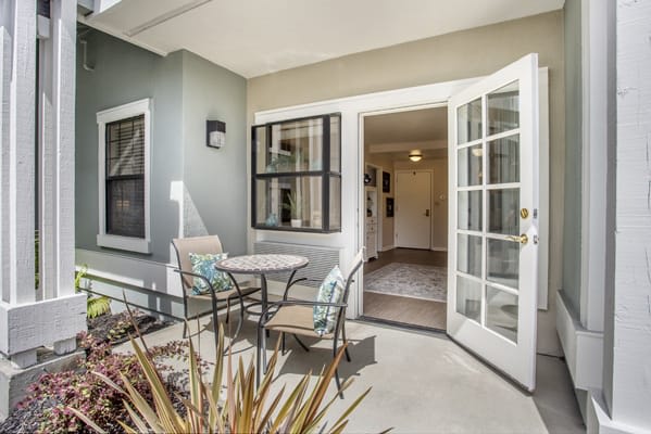 A cozy residential patio area with outdoor seating and French doors leading inside.