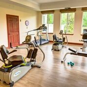 A spacious gym with various exercise equipment and large windows providing natural light.