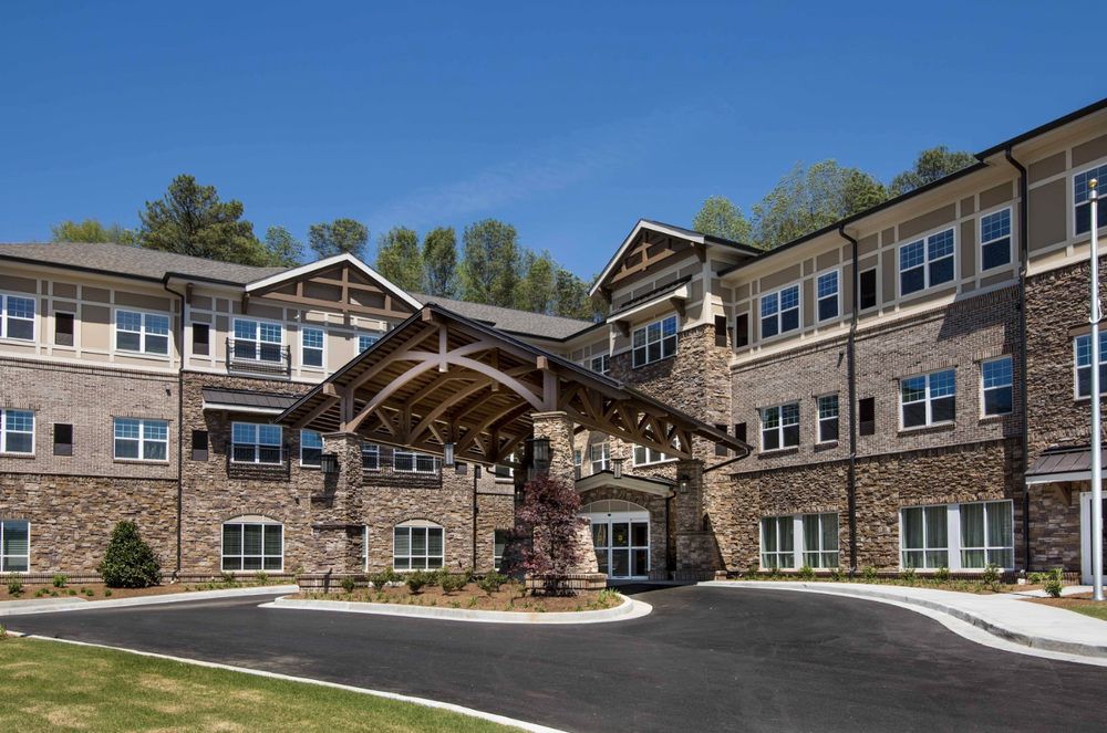A modern residential building with a stone facade and a covered entrance.