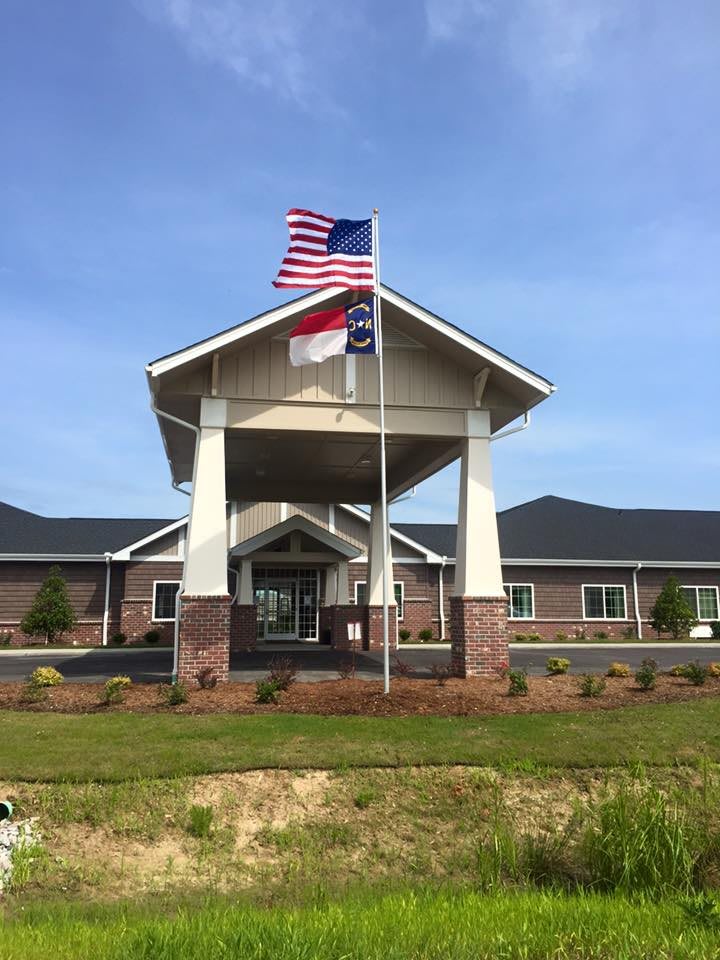 A building entrance with American and state flags flying overhead.