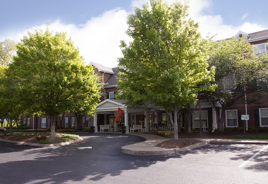 A building entrance surrounded by trees on a sunny day.