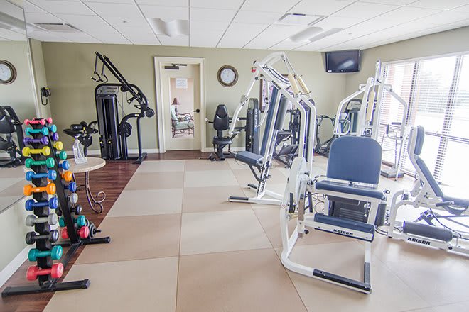 A well-equipped gym with various exercise machines arranged in a spacious indoor area.