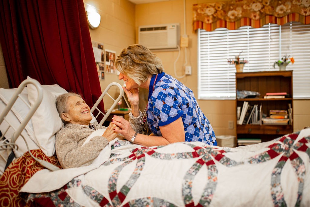 A caregiver interacts compassionately with an elderly patient in a nursing home setting.