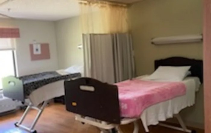 A hospital room with two beds, separated by a curtain.