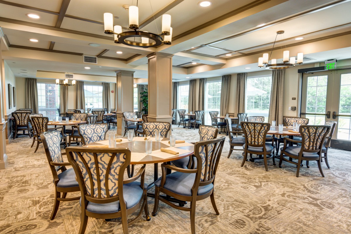 An elegant dining room with neatly arranged tables and chairs, adorned with chandeliers.