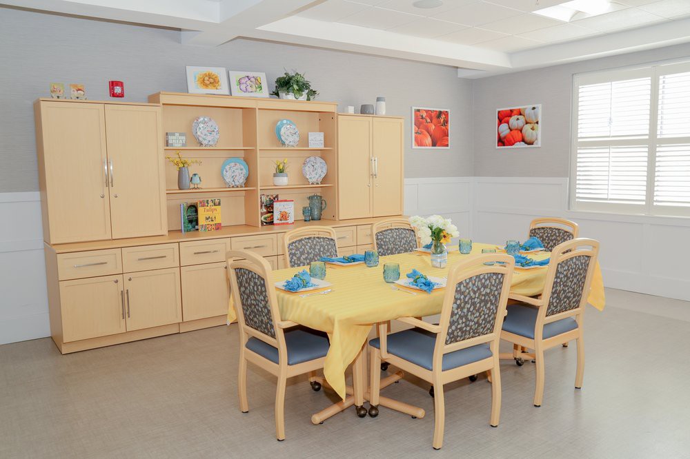 A cozy dining room with a yellow tablecloth and neatly arranged furniture.