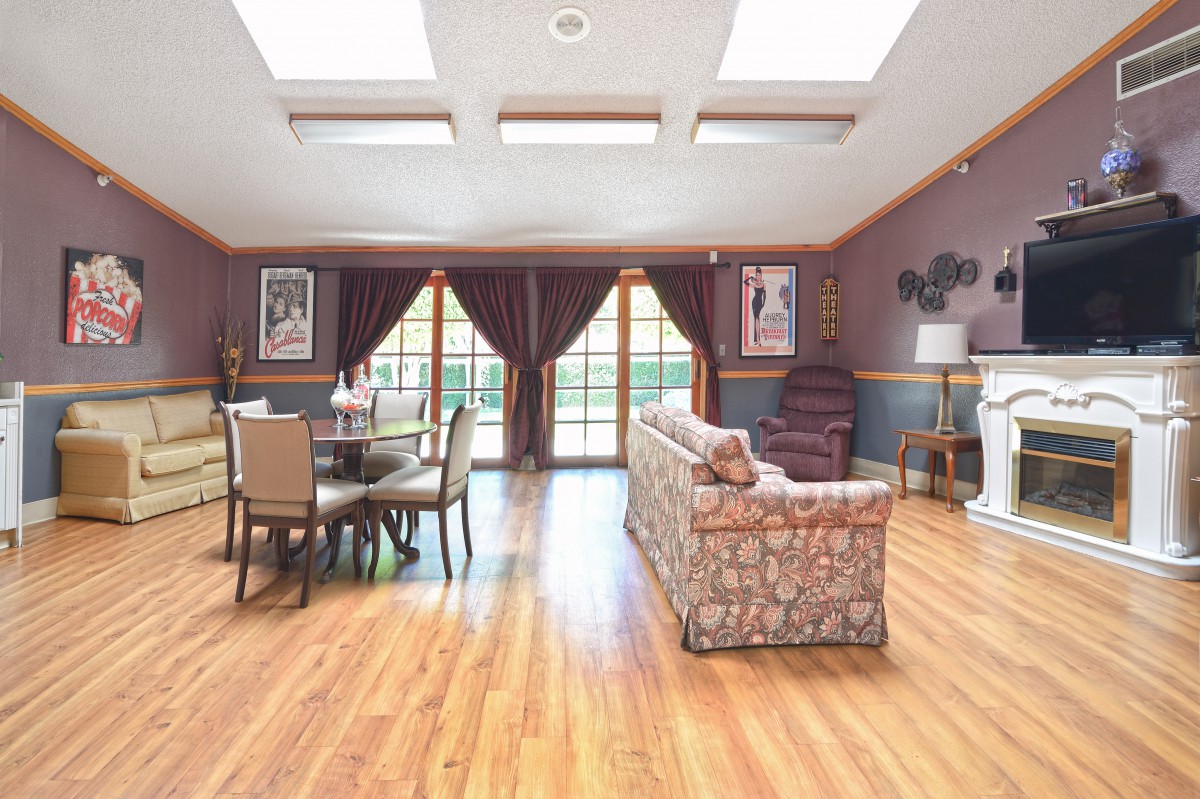 A spacious living room with large windows, skylights, and hardwood flooring.