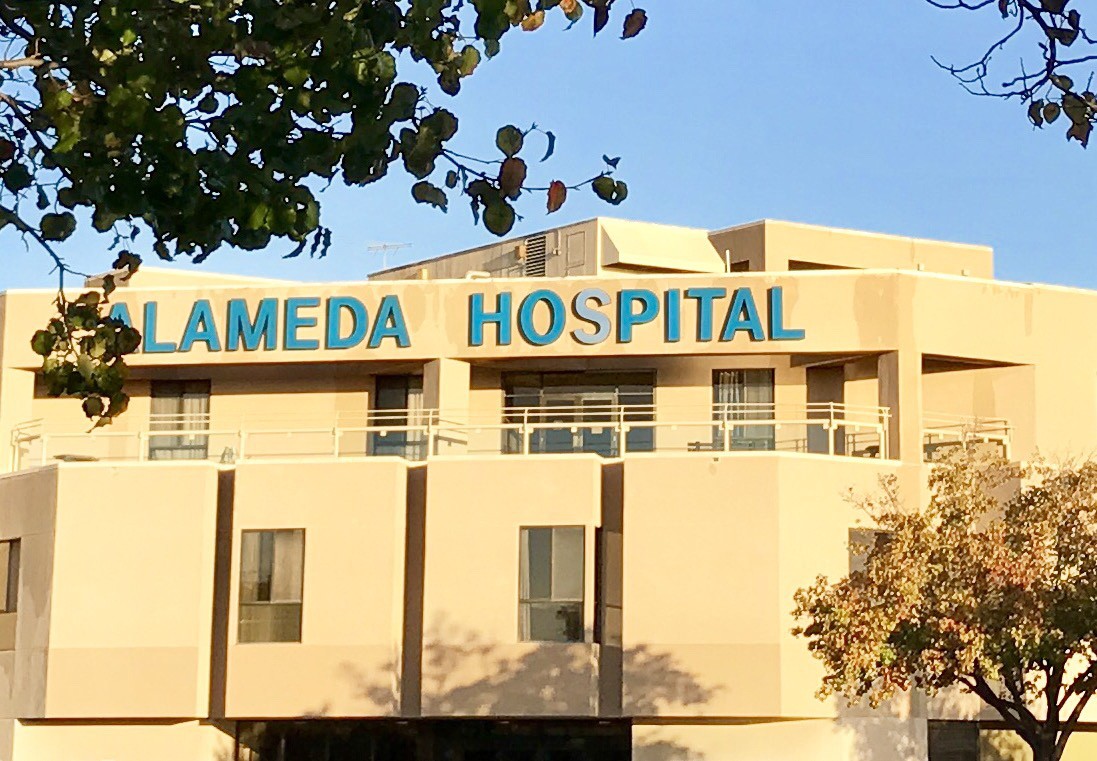 The front view of Alameda Hospital with its name displayed on the building.