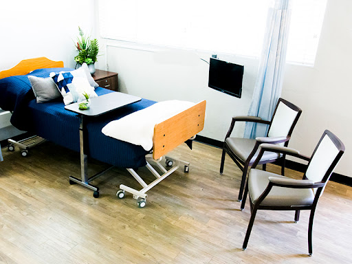 A well-designed hospital room featuring a patient bed, seating area, and natural light.