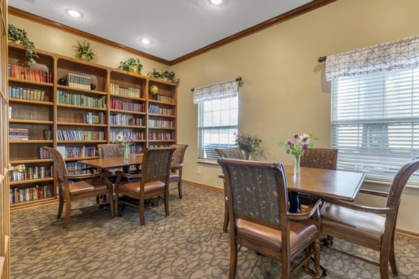 A cozy reading room with bookshelves, tables, and chairs.