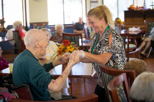 A caregiver engaging warmly with an elderly resident, fostering connection and support in a community setting.