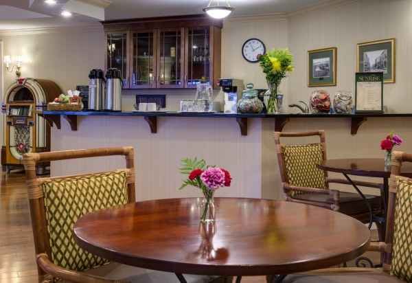 A cozy cafe interior with wooden tables, cushioned chairs, and floral decorations.