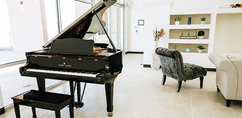 A modern living room with a grand piano and elegant furnishings.