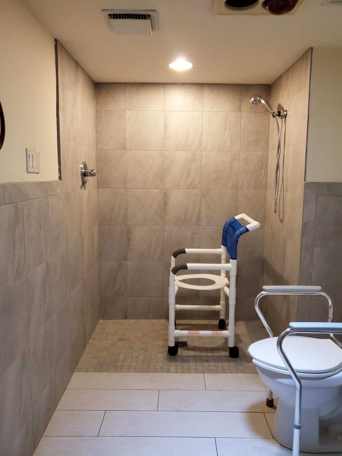 An accessible bathroom with a shower chair and handrails, designed for ease of use and safety.