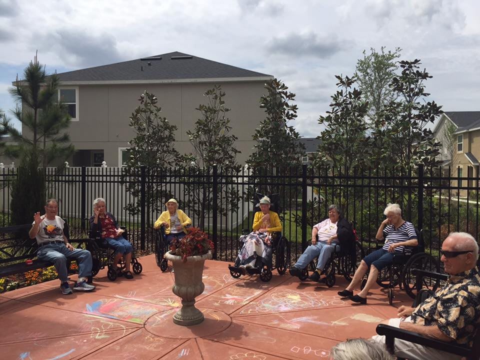 A group of seniors enjoying a social gathering outdoors in a garden area.