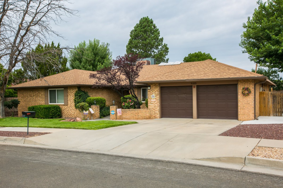 A suburban brick house with a neatly landscaped front yard and a two-car garage.