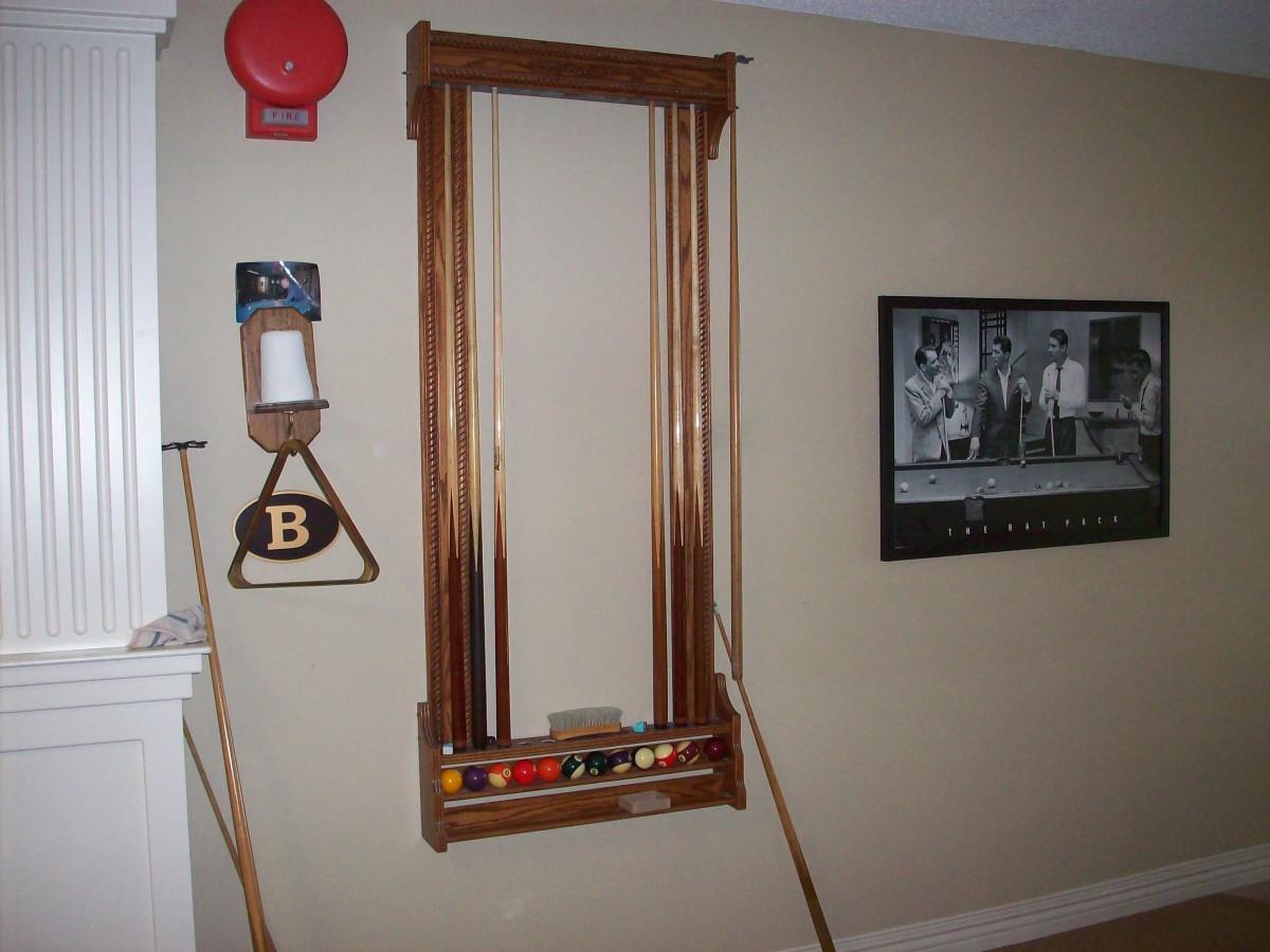 A wall-mounted pool cue rack with billiard accessories in a game room.