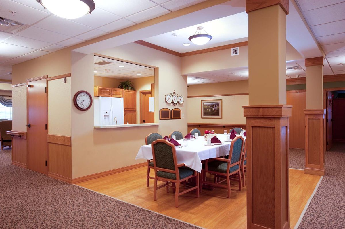 A cozy dining area with a set table and chairs under warm lighting.