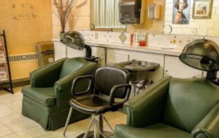 Interior view of a beauty salon with green chairs and hairdressing equipment.