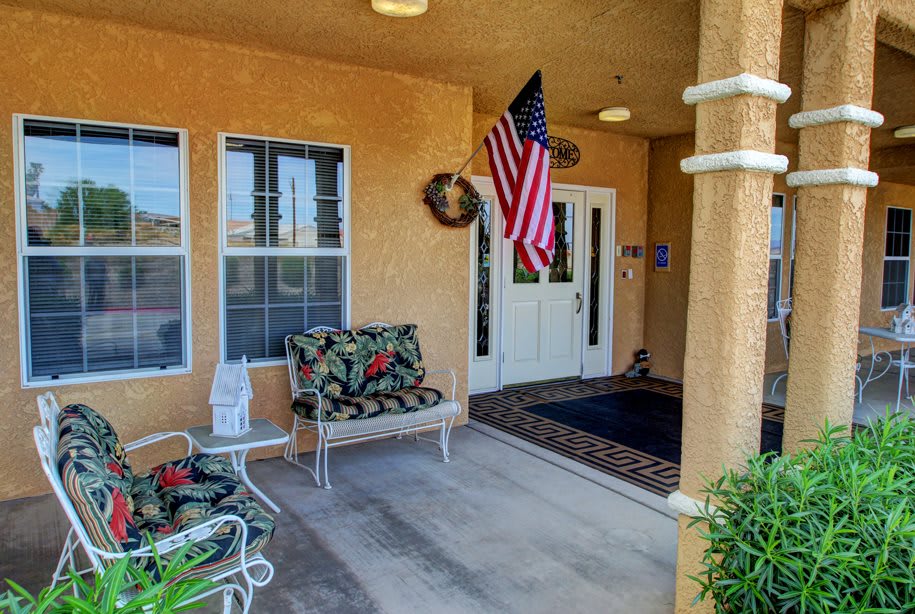 A cozy porch with a bench, American flag, and welcoming entrance.