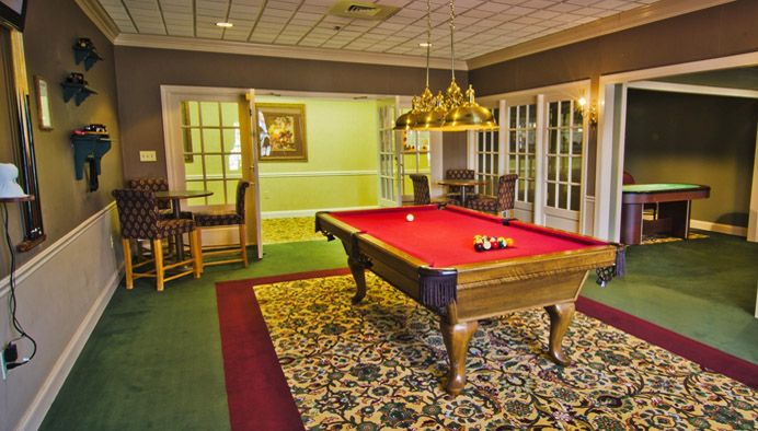 A cozy game room featuring a red-felt pool table under warm lighting.
