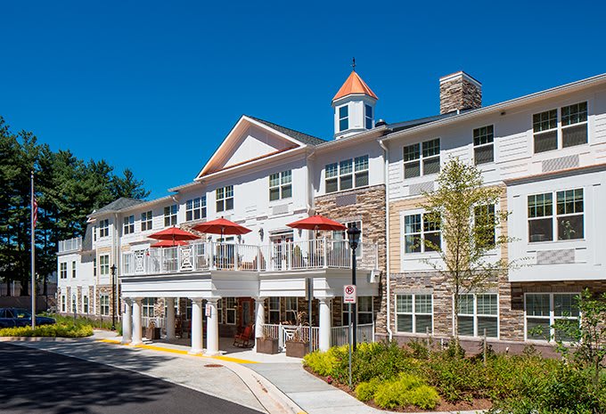 A modern residential building with balconies and red umbrellas under a clear blue sky.