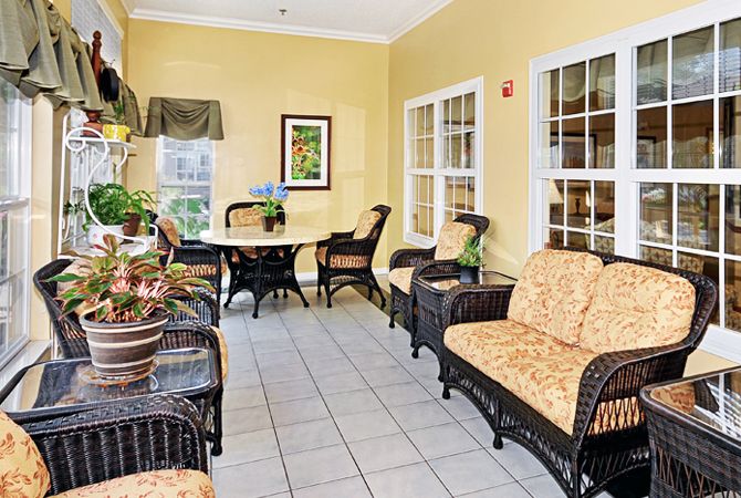 A cozy seating area with wicker furniture and yellow walls.