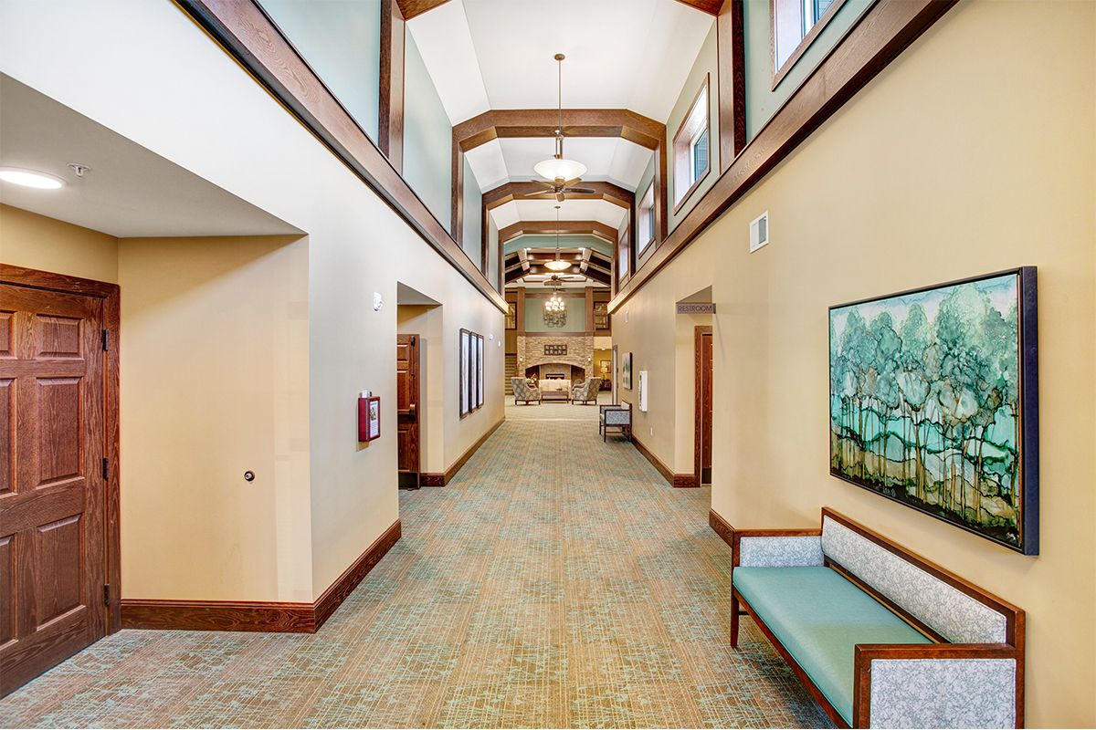 A spacious and well-lit modern hallway featuring wooden accents, seating areas, and decorative artwork.