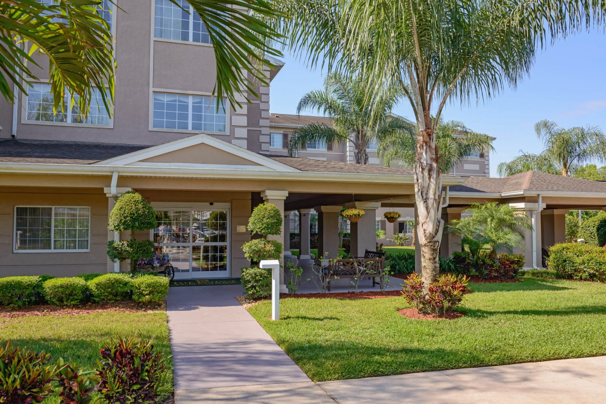 A well-maintained residential building surrounded by palm trees and lush landscaping.